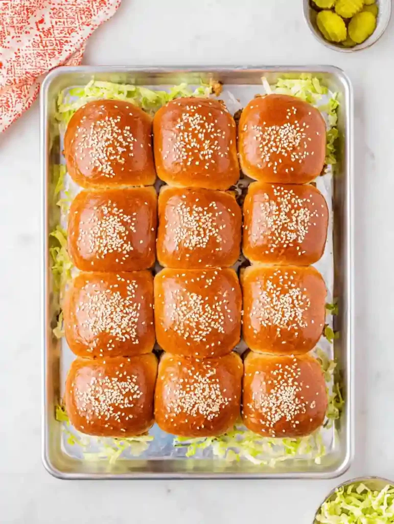 full tray of Big Mac sliders with sesame seed buns on shredded lettuce