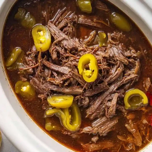 shredded Italian beef in slow cooker with pepperoncini and broth