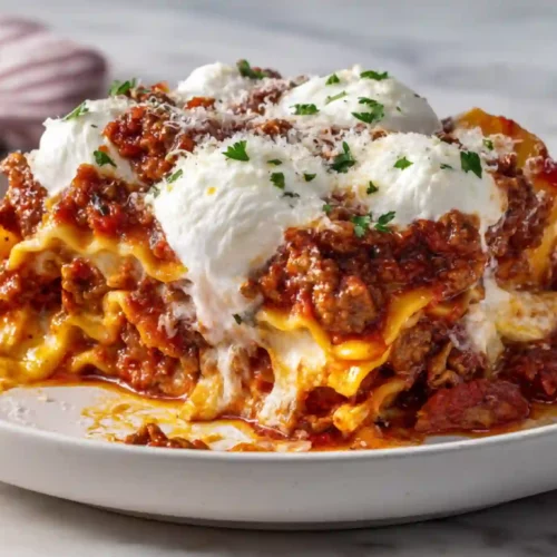 Layered cheesy skillet lasagna with rich meat sauce and fresh ricotta on a white plate