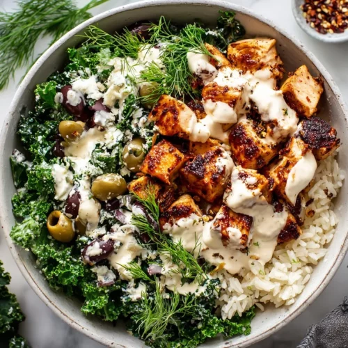 Delicious Greek Chicken Bowls with creamy tahini feta sauce on a colorful platter.