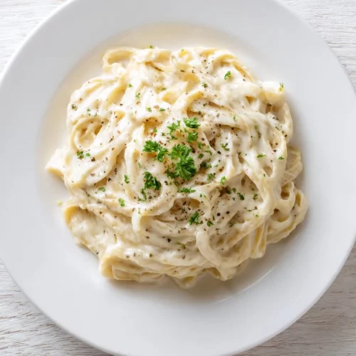 High protein cottage cheese Alfredo sauce served over pasta with herbs.