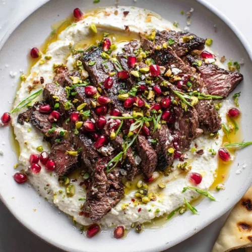 Pomegranate skirt steak garnished with whipped feta for a gourmet meal.