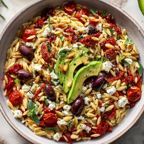 Bowl of Greek roasted red pepper tomato feta orzo topped with fresh herbs